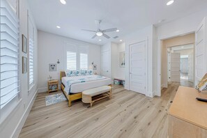 Ein Schlafzimmer mit einem Bett, Nachttischen, einem Deckenventilator und einer hölzernen Bank.