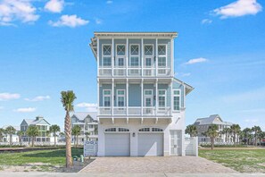 A multi-story building with a flat roof, a garage entrance, and a paved driveway. - The Sandcastle | Gulf Views | Private Elevator (Port Aransas)