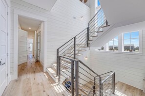 Um interior moderno com escada, piso de madeira e grandes janelas.