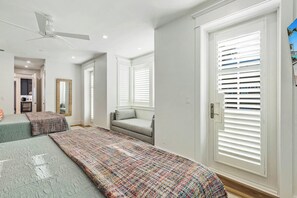 A bedroom with a bed, a sofa, a mirror, and a window with blinds. - Palmilla Pearl-Tallest In Palmilla | Gulf Front (Port Aransas)