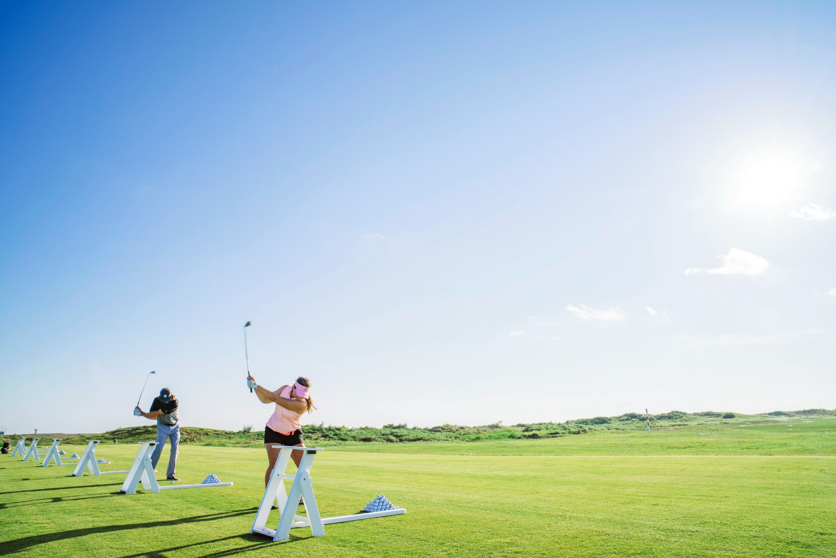 A golf course with players practicing their swings.