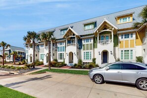 A row of modern multi-story houses with balconies, a car parked in the driveway, and well-maintained landscaping. - Indigo Mist | Steps to Beach | Resort Amenities (Port Aransas)