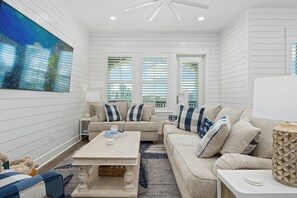A living room with a sofa, coffee table, and a painting on the wall. - Coastal Charm | Pet Friendly | Steps to Beach (Port Aransas)