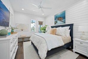 A bedroom with a bed, a nightstand, a dresser, a ceiling fan, and a window. - Coastal Charm | Pet Friendly | Steps to Beach (Port Aransas)