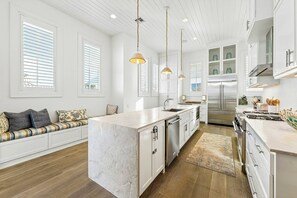 A modern kitchen with a marble island, stainless steel appliances, and a built-in oven. - Mermaid Dreams | Gulf Views | Private Elevator (Port Aransas)