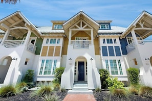 A multi-story residential building with a symmetrical facade, a central entrance with a blue door, and a balcony on the upper floor. - Gone Fishin | Pet Friendly | Steps to Beach (Port Aransas)