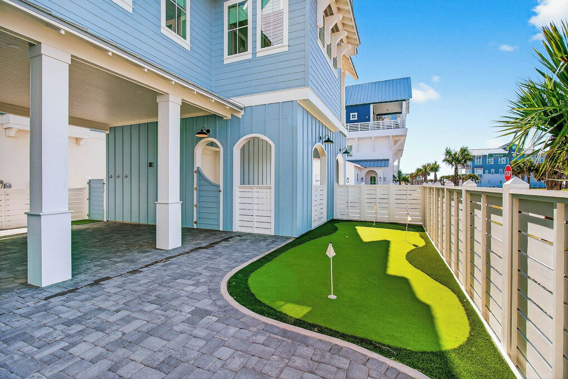 A residential property with a paved driveway, a small lawn with a golf hole, and a gated entrance.