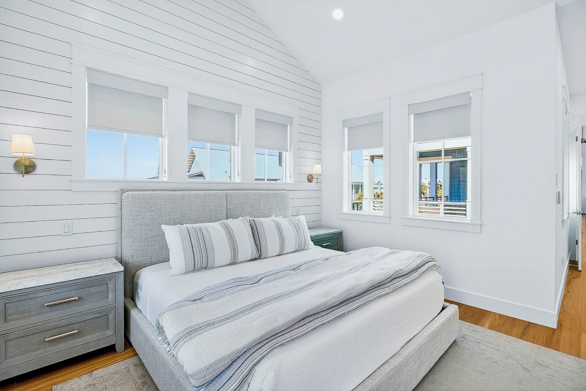 A bedroom with a bed, nightstands, and a view of the outside.