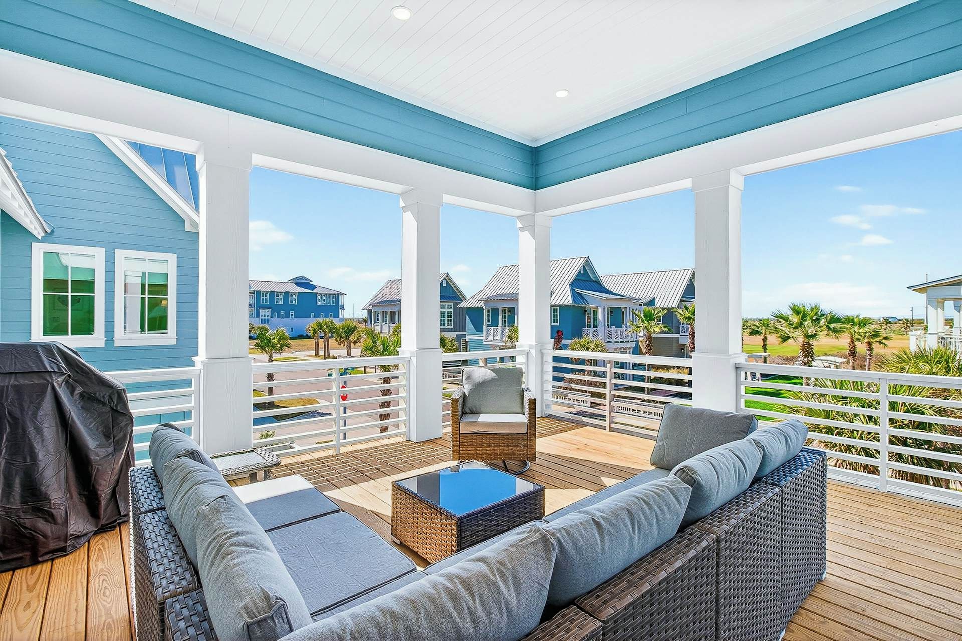 A covered outdoor seating area with a view of the ocean and beach houses.