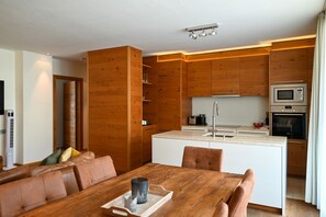 A modern kitchen with wooden cabinets, a built-in microwave, and a sink. - Zell City Exclusive Lodges TOP 3 Balcony (Zell am See)