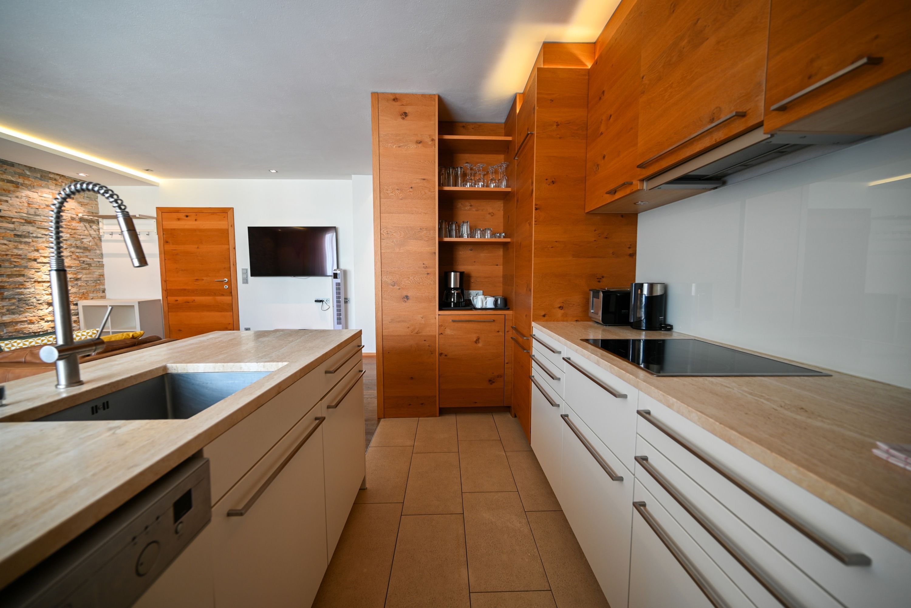 A modern kitchen with wooden cabinets, a built-in oven, and a large island with a sink.