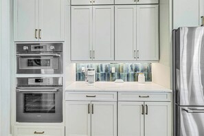 A kitchen with white cabinets, stainless steel appliances, and a tiled backsplash. - 'Merica Estate | Steps to Beach | Game Room (Port Aransas)