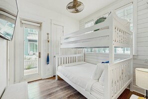 A bunk bed room with a white color scheme, a ceiling fan, and a view through the window. - Casitas Sweetbay| Resort Amenities |Steps to Beach (Port Aransas)