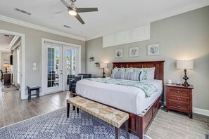 Ein Schlafzimmer mit einem Bett, Nachttischen, einer Bank und einem Deckenventilator.