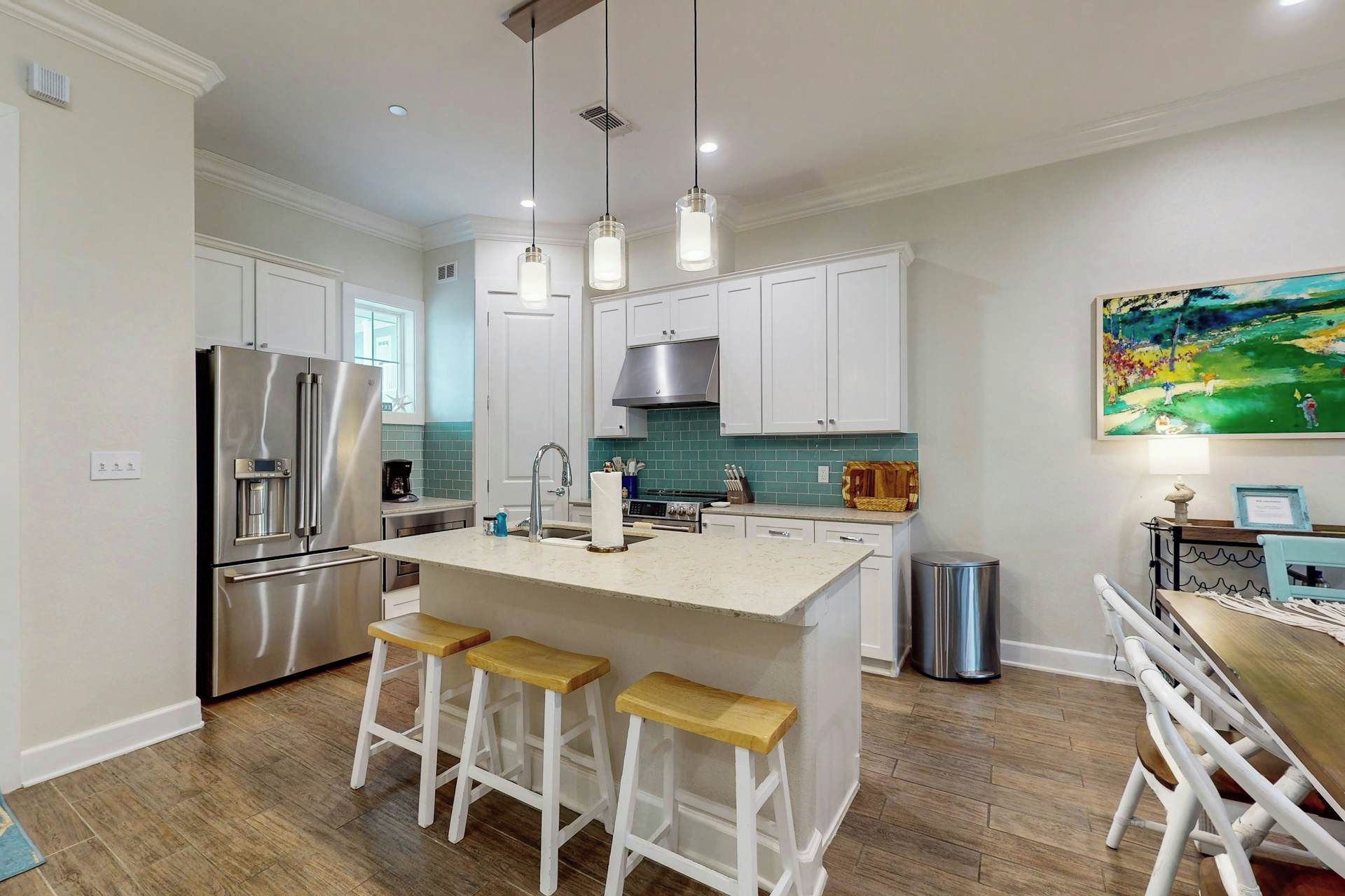 A modern kitchen with a central island, stainless steel appliances, and a dining area with a table and chairs.