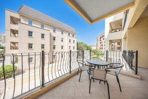 Ein Balkon mit Tisch und Stühlen, der auf eine Straße mit Gebäuden blickt.