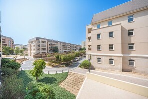 Ein Wohngebäude mit mehreren Balkonen, einem angelegten Garten und blauem Himmel.