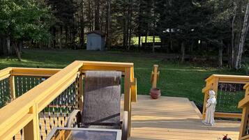 A wooden deck with a table and chairs, surrounded by a forest.