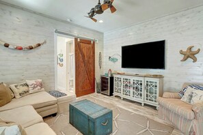 Ein Wohnzimmer mit Holzboden, einer Couch, einem Couchtisch, einem Fernseher und einem Schrank.