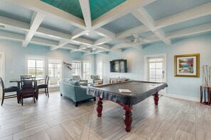 A spacious room with a pool table, a sofa, and a television. - Big Blue | Water Views | Private Pool | Game Room (Port Aransas)