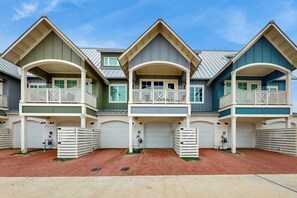 A row of three-story houses with attached garages, each featuring a balcony and a garage door. - Casita Bonita | Gulf Views | Pet Friendly (Port Aransas)