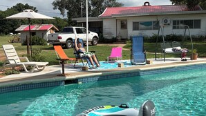 Une piscine avec des chaises longues et une maison en arrière-plan.