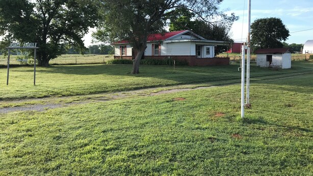 Une zone herbeuse avec une maison blanche, un mât de drapeau et un panneau indiquant « Domaine de la famille Jones ».