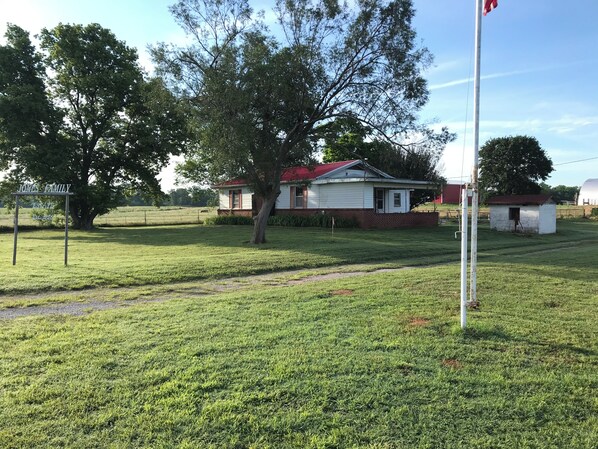 A grassy area with a white house, a flagpole, and a sign that reads 'Jones Family Estate'.