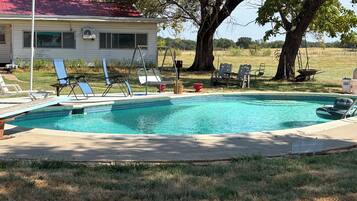 A swimming pool with lounge chairs and a house in the background.