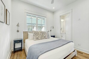 Ein Schlafzimmer mit Bett, Nachttischen, einem Fenster und einer Tür.