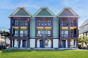 Ein mehrgeschossiges Wohngebäude mit symmetrischer Fassade, mehreren Balkonen und einem zentralen Eingang mit einer Tür.