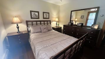 A bedroom with a bed, bedside tables, a dresser, a ceiling fan, and a mirror.