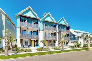 A row of modern multi-story buildings with balconies, a flat roof, and a well-maintained lawn. - Coastal Vista Retreat | Pet Friendly (Port Aransas)
