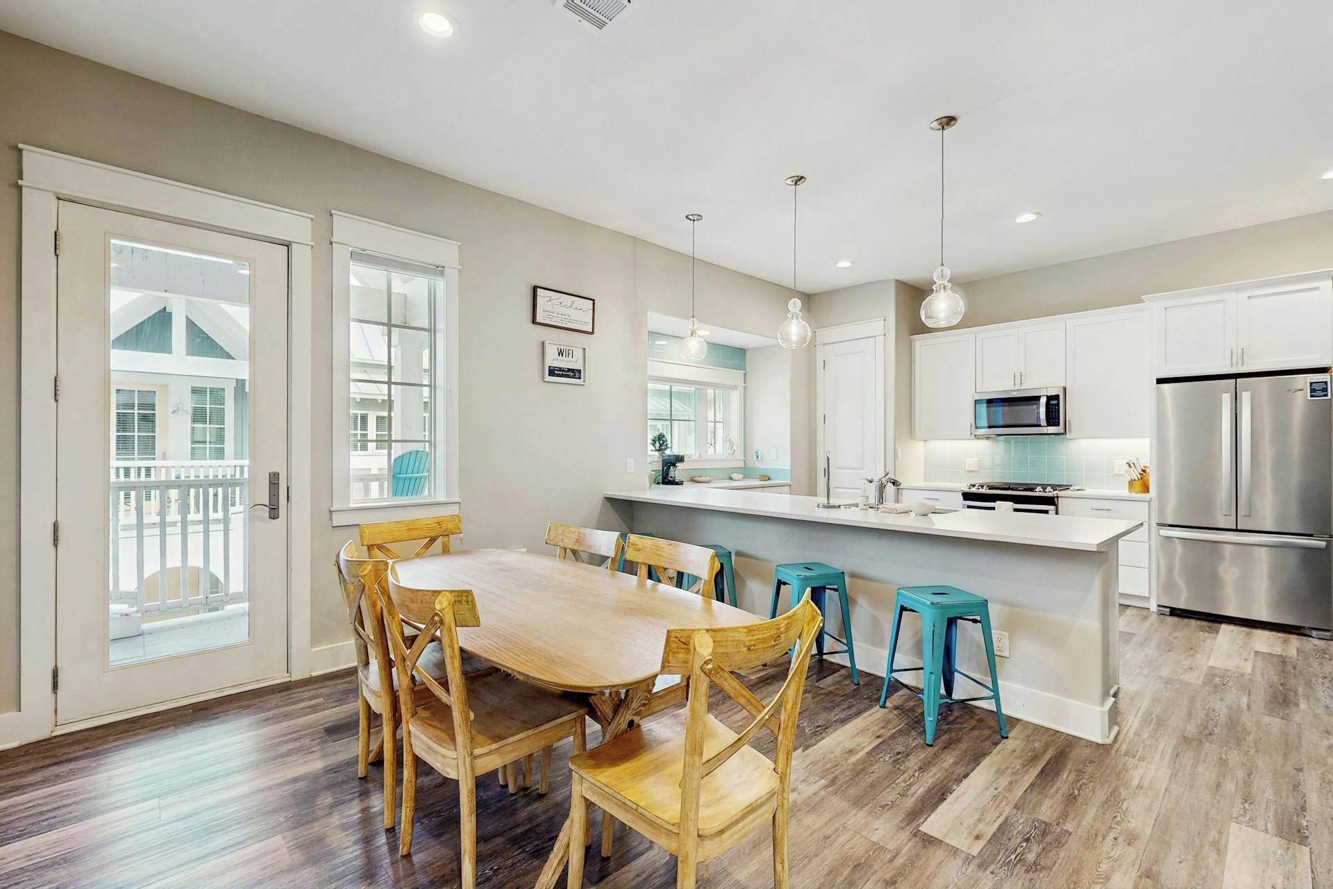 Una cocina moderna con una isla central, electrodomésticos de acero inoxidable y un comedor con sillas de madera.