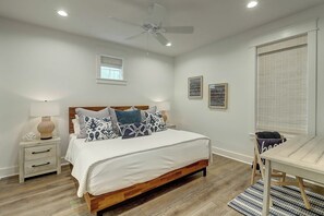 Ein Schlafzimmer mit einem Holzbett, Nachttischen, einem Deckenventilator und einem Fenster mit Jalousien.