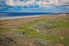 Ein Golfplatz an der Küste mit Blick auf den Ozean und einen Strand.