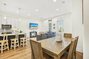 A modern kitchen with white cabinets, a microwave, and pendant lights. - Driftwood Cottage | Golf Views | Pet Friendly (Port Aransas)
