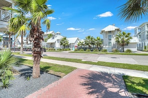 A residential street with houses, palm trees, and a clear sky. - Beach Please | Steps to Beach | Resort Amenities (Port Aransas)