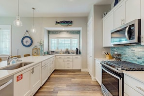 A kitchen with white cabinetry, a stainless steel range, and a microwave. - Beach Please | Steps to Beach | Resort Amenities (Port Aransas)