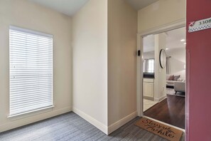 A hallway with a door leading to a living area, a doormat with 'Stay Home' text, and a number '3308' on the wall. - The Northstar Condo - Minnesota meets Bama (Tuscaloosa)