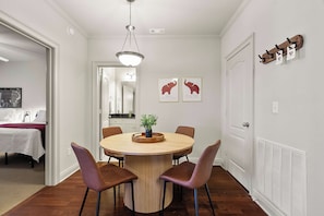 A dining area with a round table, four chairs, a vase with greenery, and two framed pictures on the wall. - The Northstar Condo - Minnesota meets Bama (Tuscaloosa)