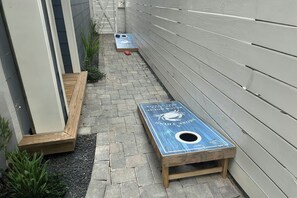 A narrow outdoor space with a shuffleboard table and a wooden bench. - A Shore Thing | Gulf Views | Steps to Beach (Port Aransas)