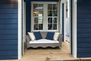 A wicker bench with cushions in front of a window with multiple panes. - A Shore Thing | Gulf Views | Steps to Beach (Port Aransas)