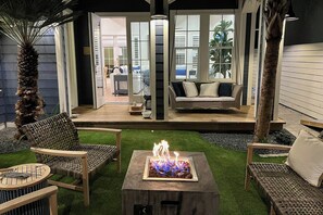 Eine Außenpatio mit Feuerstelle, Korbmöbeln und Blick ins Haus.