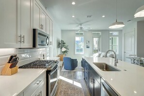 A modern kitchen with white cabinetry, a built-in oven, and a large island with a sink. - Beaches And Bunkers | Golf Views | Pet Friendly (Port Aransas)