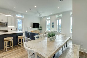 A modern kitchen with white cabinetry, a built-in microwave, and a large island with bar stools. - Beaches And Bunkers | Golf Views | Pet Friendly (Port Aransas)
