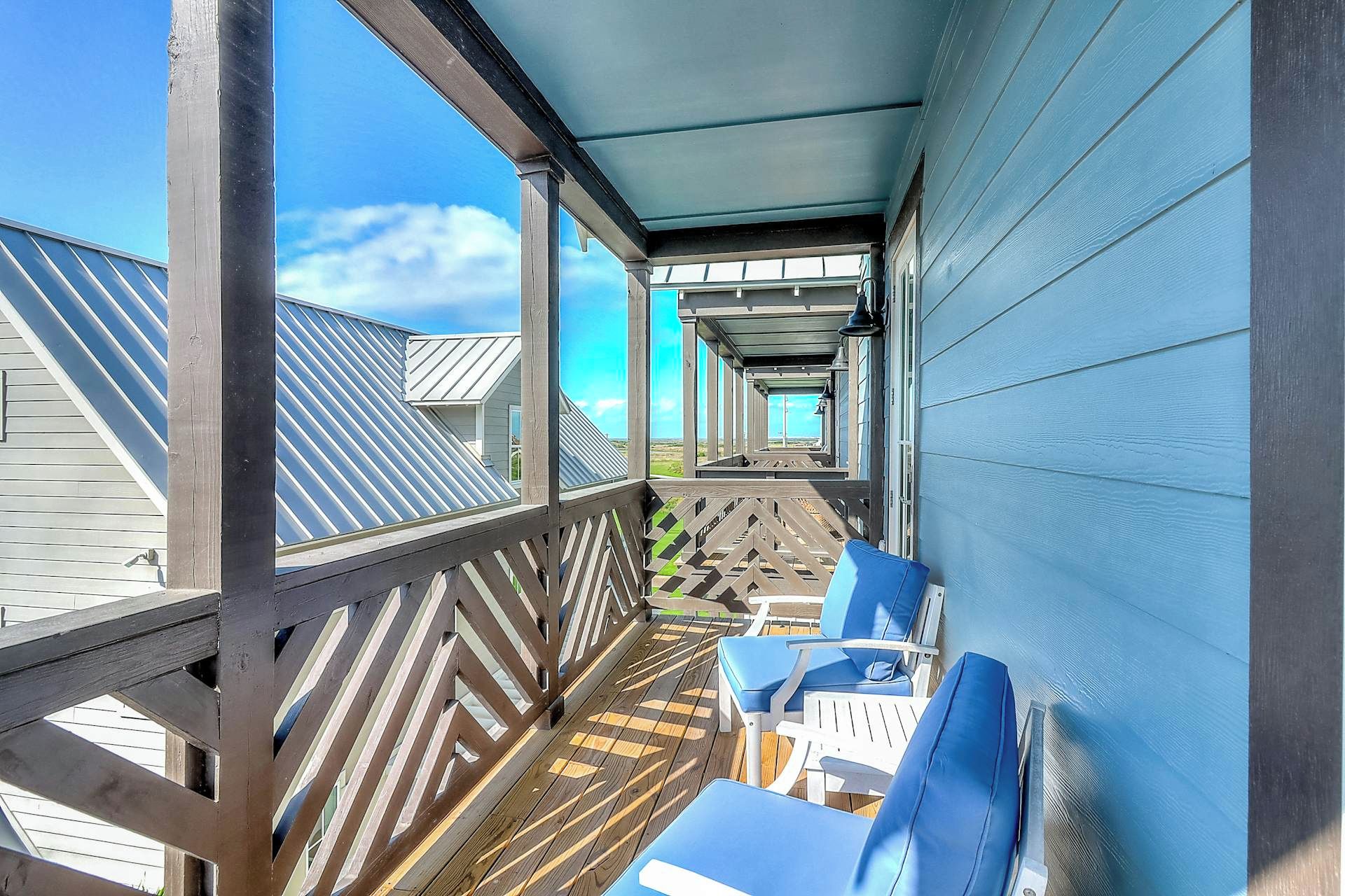Eine überdachte Terrasse im Freien mit Holzbalkonen und blauen Stühlen.