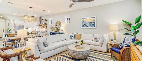 A modern living room with a sectional sofa, a round coffee table, and a ceiling fan.