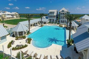 Ein Resort mit großem Schwimmbecken, Liegestühlen und Blick auf den Ozean.