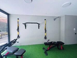 Une salle de sport équipée de matériel d’exercice, d’un banc et d’une fenêtre.
